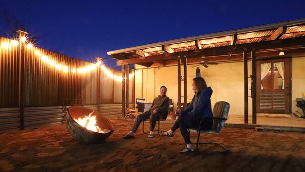 An outdoor seating area with a fire pit, a covered patio, and a rustic building facade.