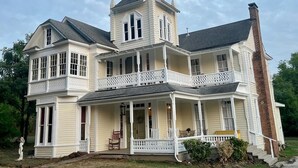 A large, two-story house with a wrap-around porch and a tower on the second floor. - Take a trip back in time and stay at the Larissa House Inn! (Jacksonville)