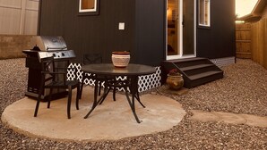 Kaksikerroksinen talo, jossa on patio, grilli ja ulkotila istumista varten.