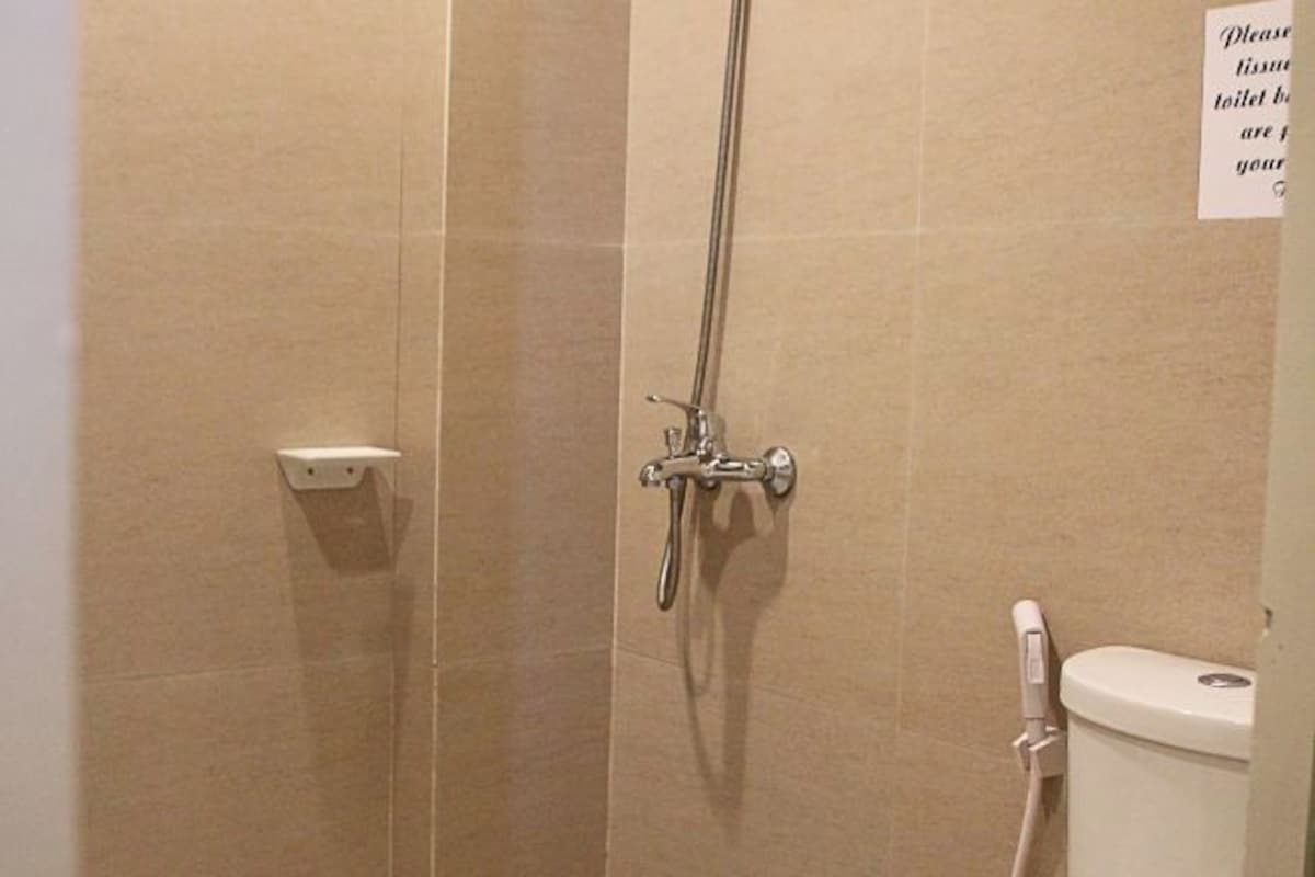 Zona de ducha con grifo empotrado en la pared y un inodoro.