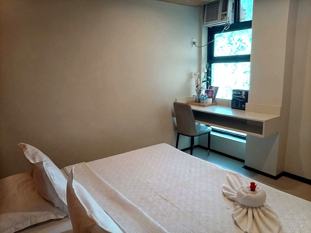 A room with a bed, a desk, a chair, and a window with blinds.