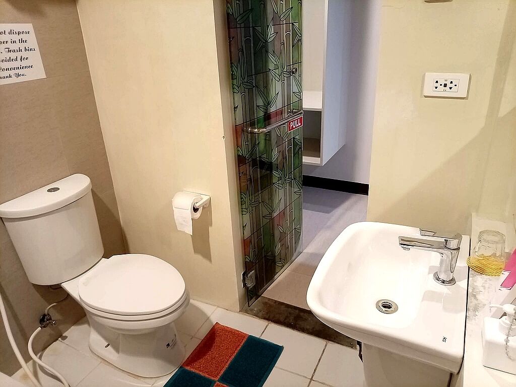 A bathroom with a toilet, sink, and a patterned glass door.