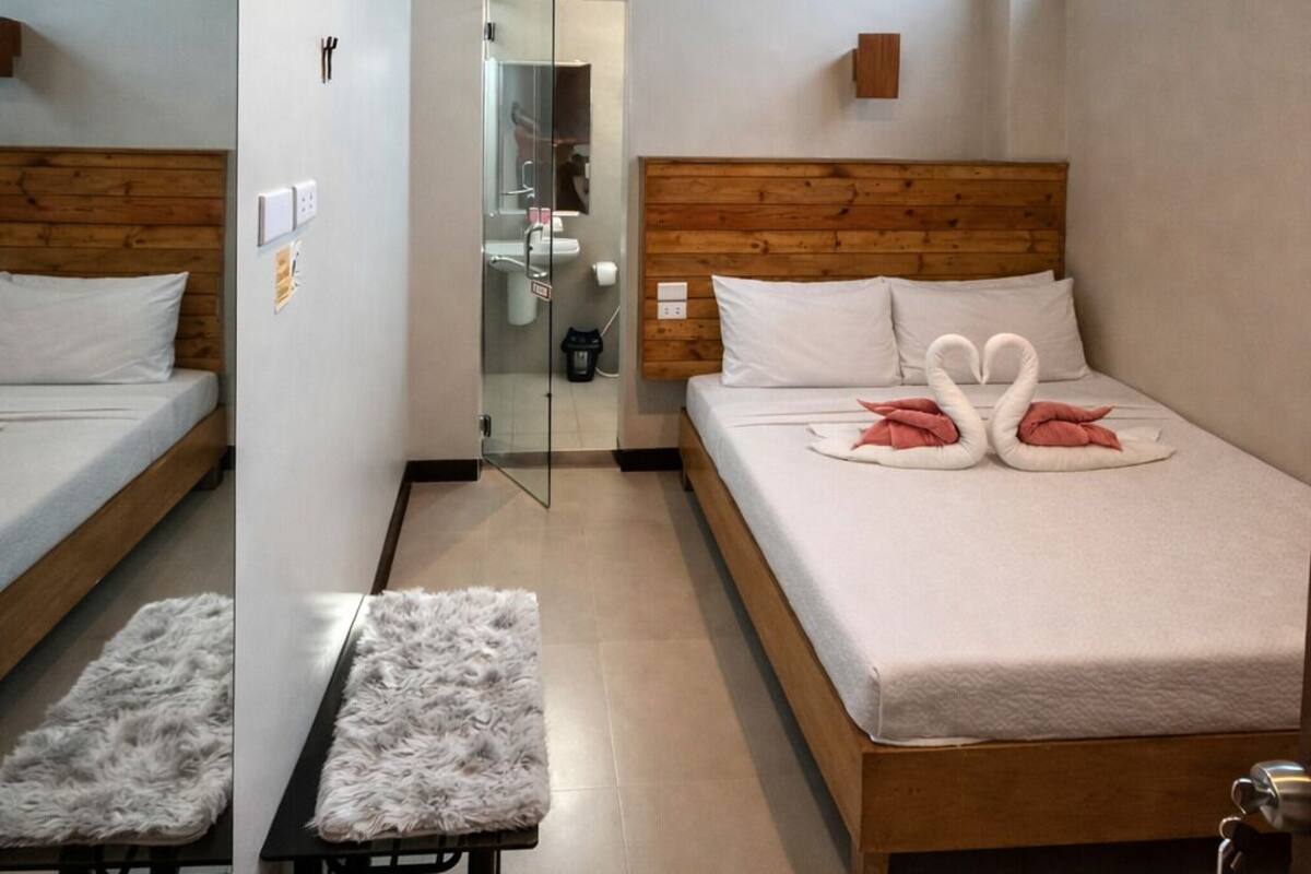 A modern hotel room with a wooden ceiling, a large bed with a swan decoration, a bench, and a mirror.