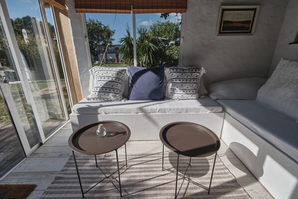 A modern living room with a sofa, two small tables, and a large window.