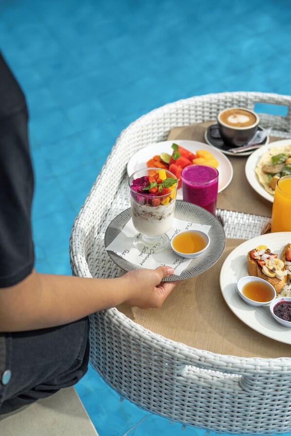 A wicker table with a tray holding a meal, a glass of juice, and a cup of tea.