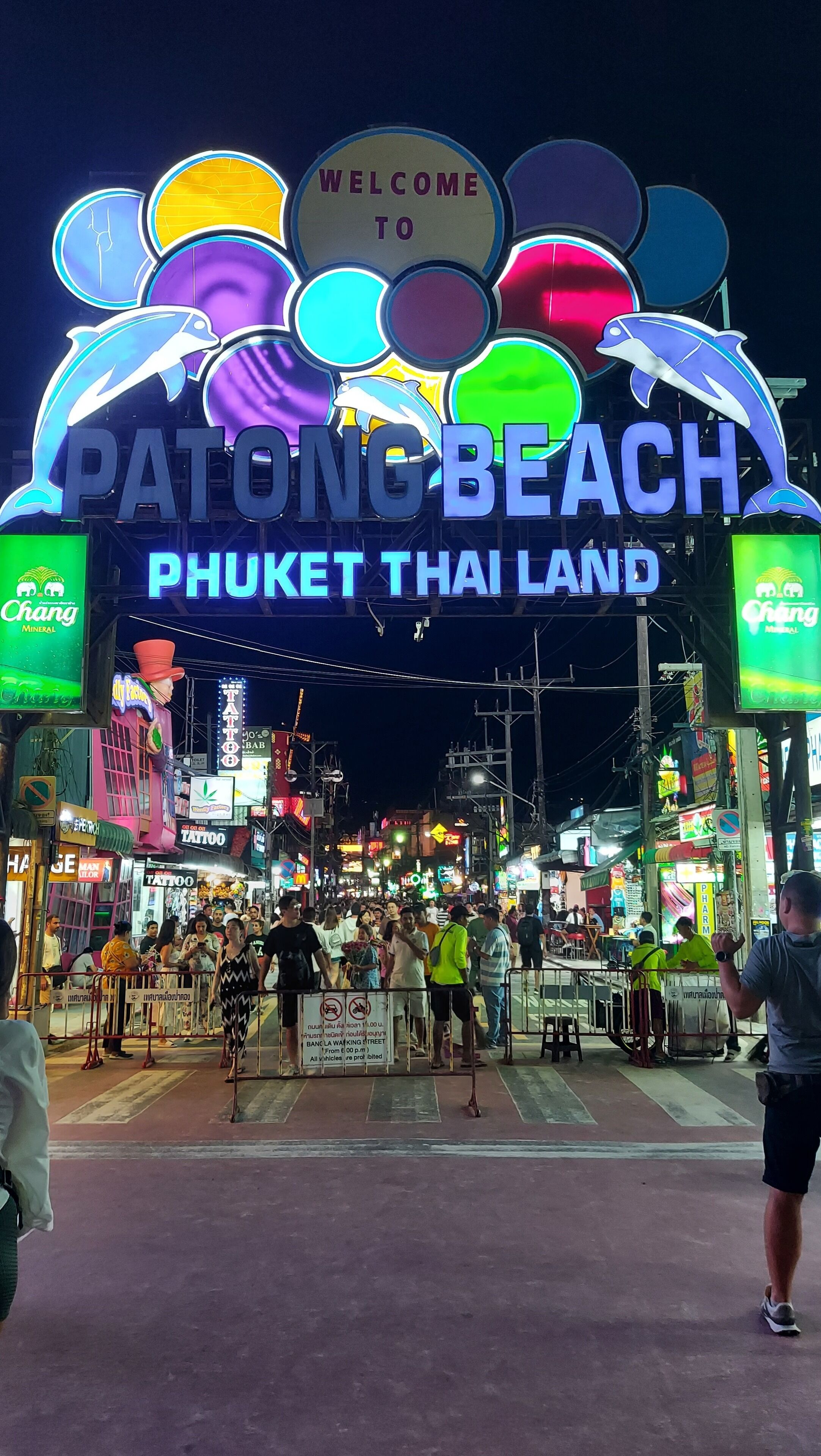 En neonlys-skilt byder besøgende velkommen til Patong Beach i Phuket, Thailand, mens en menneskemængde har samlet sig nedenfor.