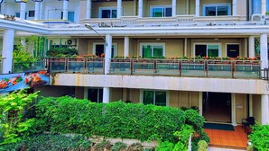 A multi-story hotel with balconies, a covered outdoor seating area, and lush greenery. - Sawasdee Apartment Patong (Patong)