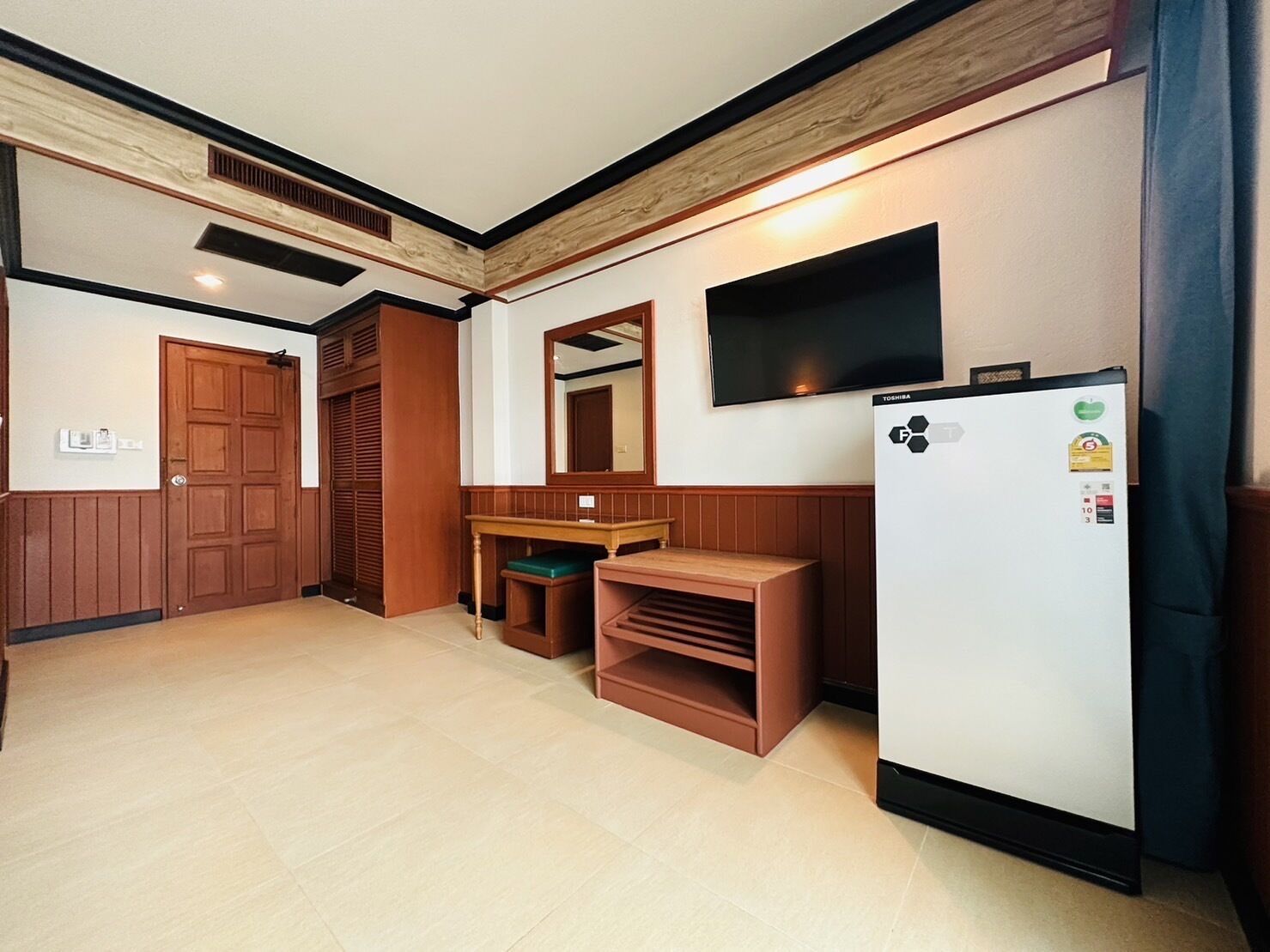 Eine kleine Küche mit Kühlschrank, Holzschränken, Mikrowelle und Backofen.