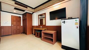 A compact kitchen with a refrigerator, wooden cabinets, a microwave, and a built-in oven.