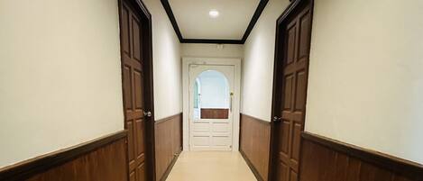 A hallway with wooden paneling on the walls and a beige tiled floor.