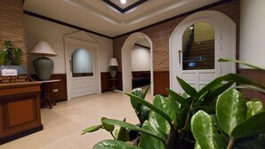 A hallway with a reception desk, a check-out sign, a large vase, and a mirror. - Sawasdee Apartment Patong (Patong)
