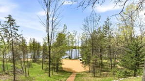 A pathway leading to a sandy beach surrounded by trees.