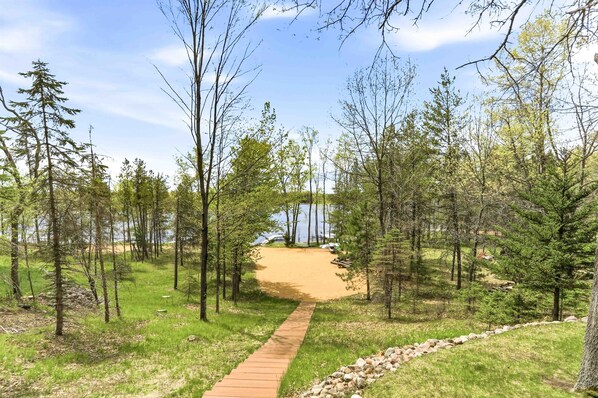 A pathway leading to a sandy beach surrounded by trees.