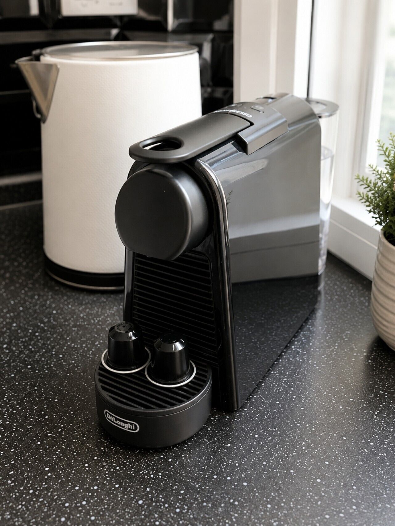 A coffee machine on a kitchen counter with a white kettle in the background.