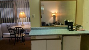 A compact kitchenette with a refrigerator, a coffee maker, and a small dining area with a table and chairs. - Alpine Lodge Motel (Grande Cache)