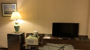 A hotel room with a television, a lamp, a coffee maker, and a trash bin. - Alpine Lodge Motel (Grande Cache)