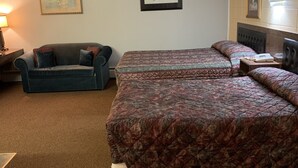 A hotel room with two beds, a sofa, a nightstand, and a lamp. - Alpine Lodge Motel (Grande Cache)