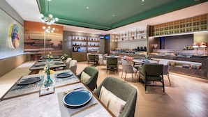 A restaurant with a green ceiling, multiple dining tables, and chairs. There are shelves with bottles and glasses, and a counter with a menu. - Beijing Tiananmen Qianmen Manxin Hotel (Beijing)