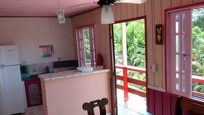 A kitchen with a dining area, a refrigerator, a sink, and a window with a view of greenery. - Chalé Mirante do Félix Ubatuba  (Ubatuba)