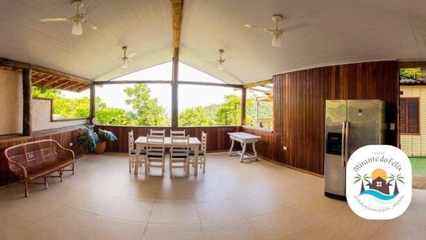 A covered outdoor dining area with a table and chairs, ceiling fans, and a refrigerator. - Chalé Mirante do Félix Ubatuba  (Ubatuba)