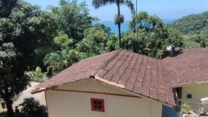 A small building with a tiled roof, surrounded by lush greenery and palm trees. - Chalé Mirante do Félix Ubatuba  (Ubatuba)