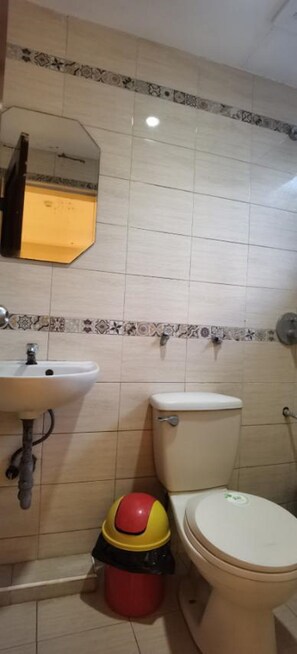 A bathroom with a sink, toilet, and a red and yellow bucket. - G Hotel powered by Cocotel (San Juan)