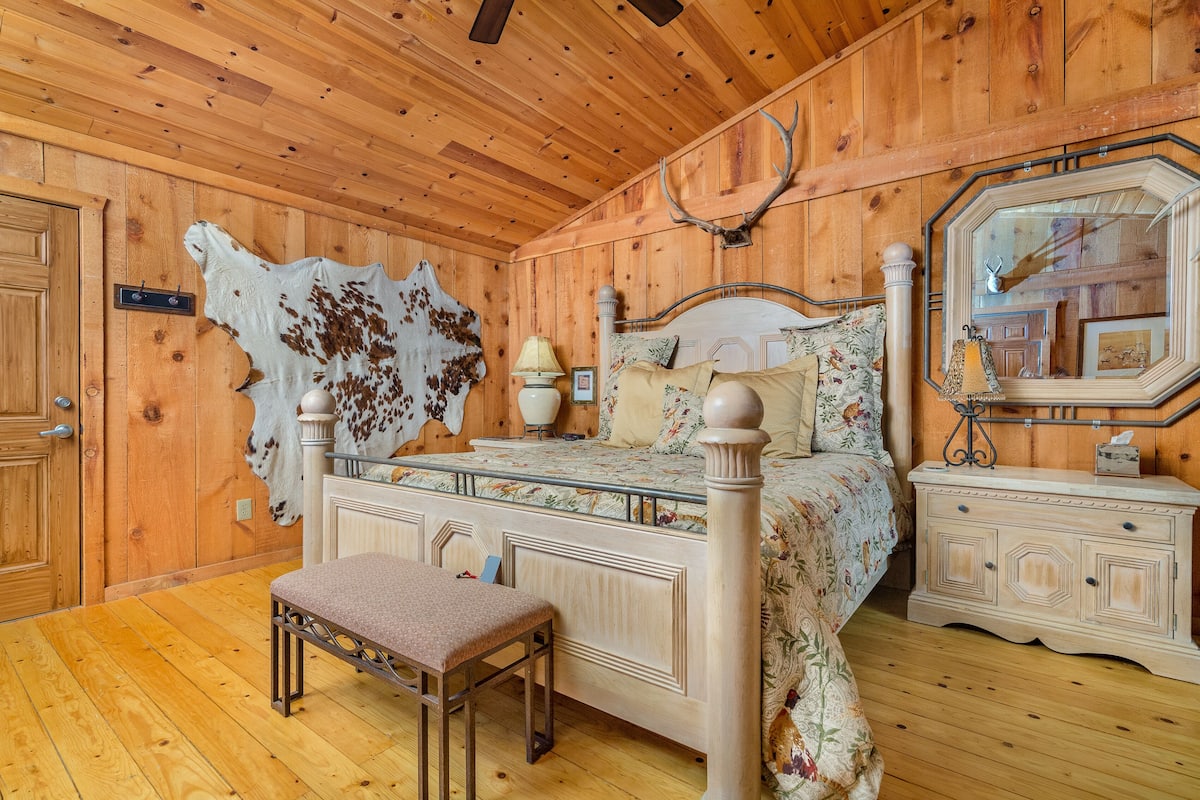 Une chambre aux murs lambrés, avec un lit, un banc et un grand miroir.