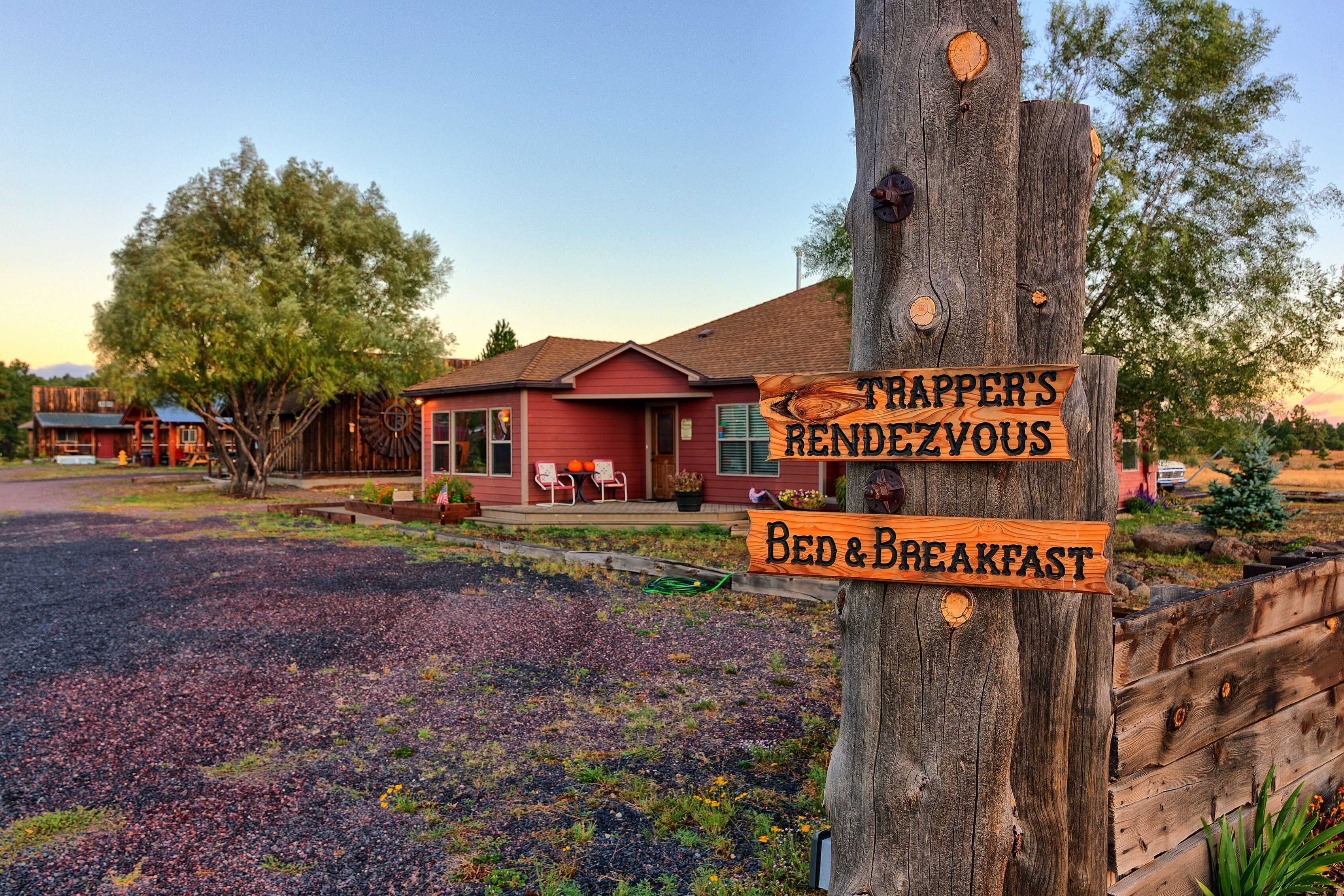 Un letrero de madera con 'TRAPPER'S BENDZIOUS' y 'BED & BREAKFAST' escrito, que indica un hospedaje y desayuno.