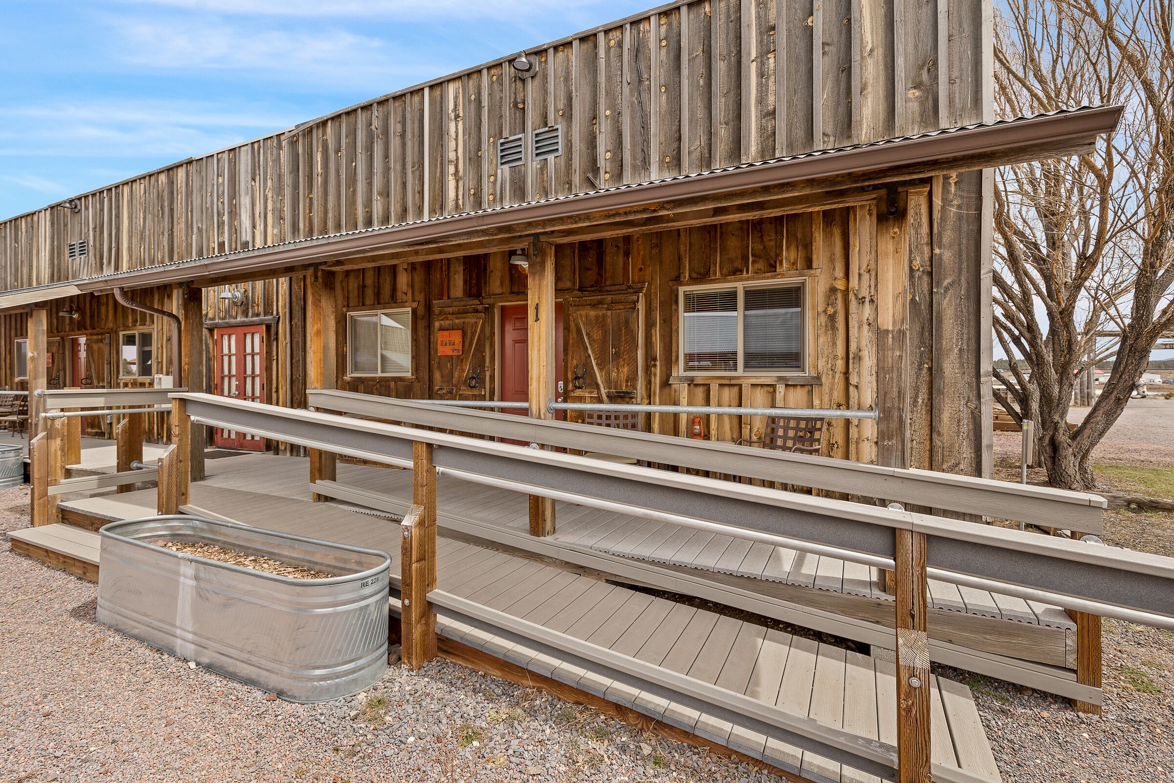 A rustic wooden building with a wooden ramp leading to a covered area.