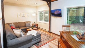 Una sala acogedora con un sofá, una mesa de comedor y un televisor montado en la pared.
