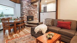 Una sala de estar con chimenea de ladrillo, un sofá, una mesa de comedor con sillas y una mesa auxiliar.