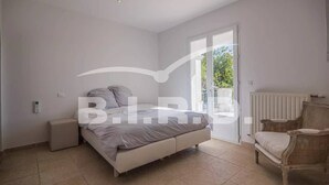 A bedroom with a bed, a chair, and a radiator. - Modern villa in the prestigious golf domain (STE MAXIME)