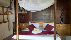 Ein Bett mit Baldachin, einem Holzkopfende und Kissen.