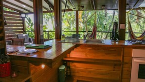 A wooden kitchen with a large window overlooking lush greenery.