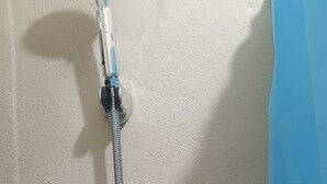 A shower with a hose and a circular control panel. - Luisandro (Punta Cana)