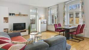 Un salon moderne comprenant un canapé, un téléviseur, une table à manger et des chaises.