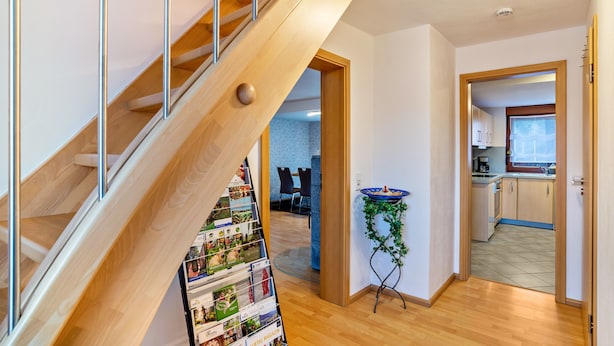 Ein modernes Interieur mit einer Holztreppe, einer Küchenzeile und einem Essbereich.