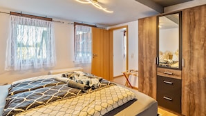 Ein Schlafzimmer mit Bett, Kleiderschrank und Spiegel.