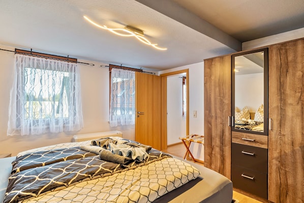 A bedroom with a bed, a wardrobe, and a mirror.