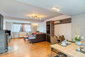 A modern living room with a fireplace, sofa, dining table, and built-in bookshelves.