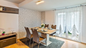 Ein moderner Essbereich mit Holztisch, Stühlen und Blick durch große Fenster.