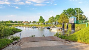Ein Kanal mit Booten, einer kleinen Brücke und einem grünen Zaun.