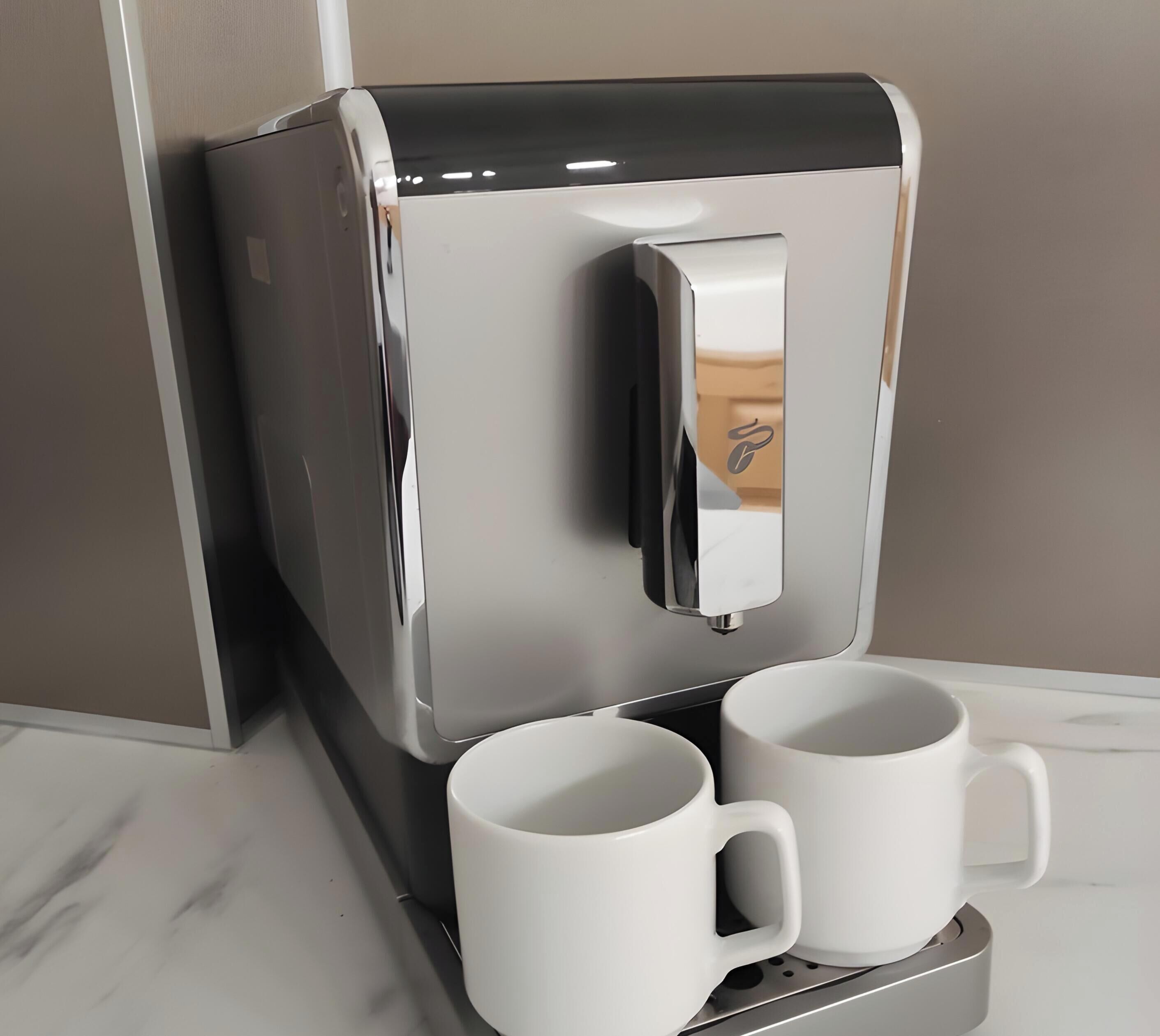 A coffee machine with two white mugs placed below it.