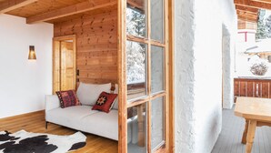 Un interior de madera con un sofá, un tapete de cuero de vaca y un ventanal grande.