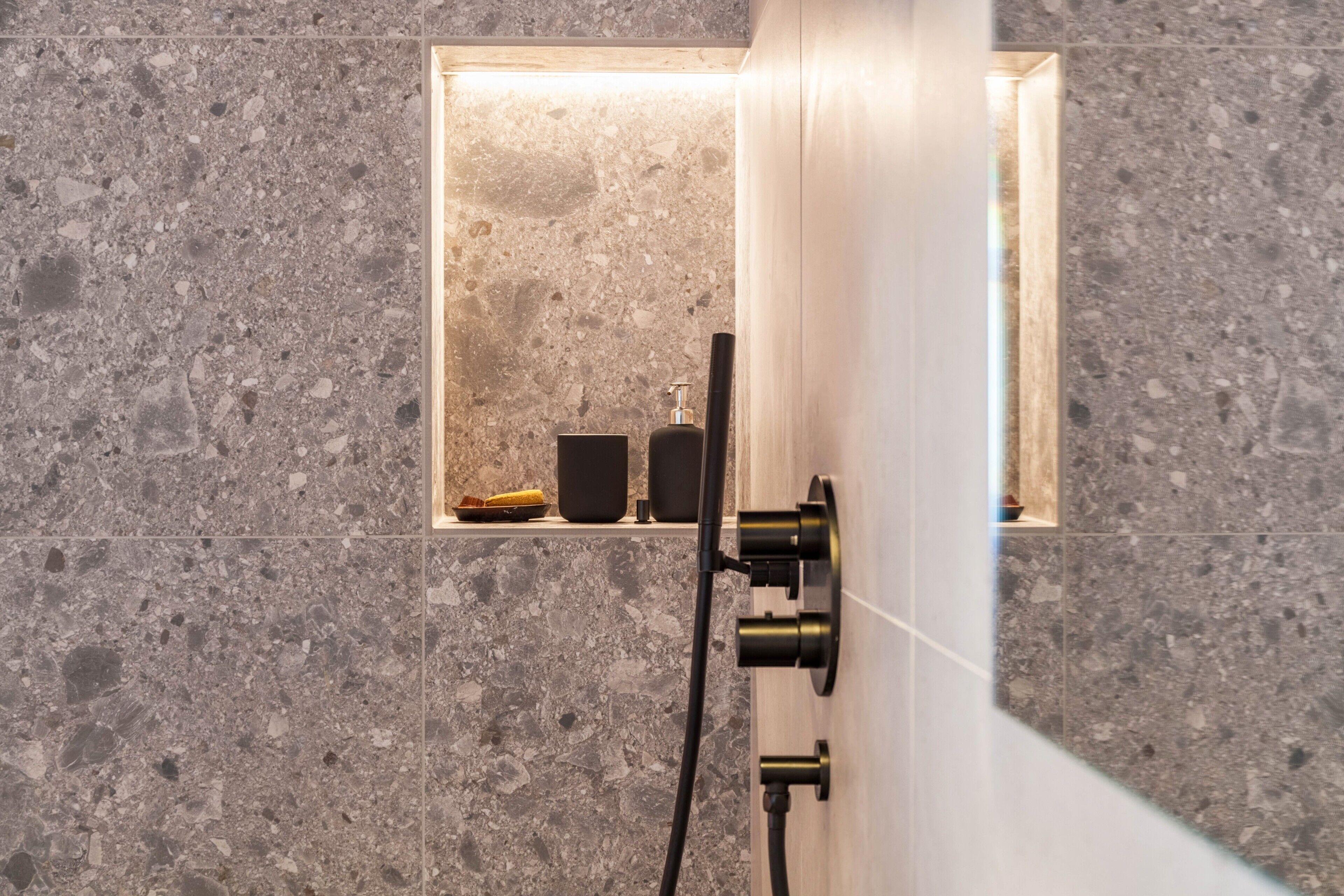 Uma casa de banho moderna com chuveiro integrado, um porta-toalhas e um dispensador de sabonete.