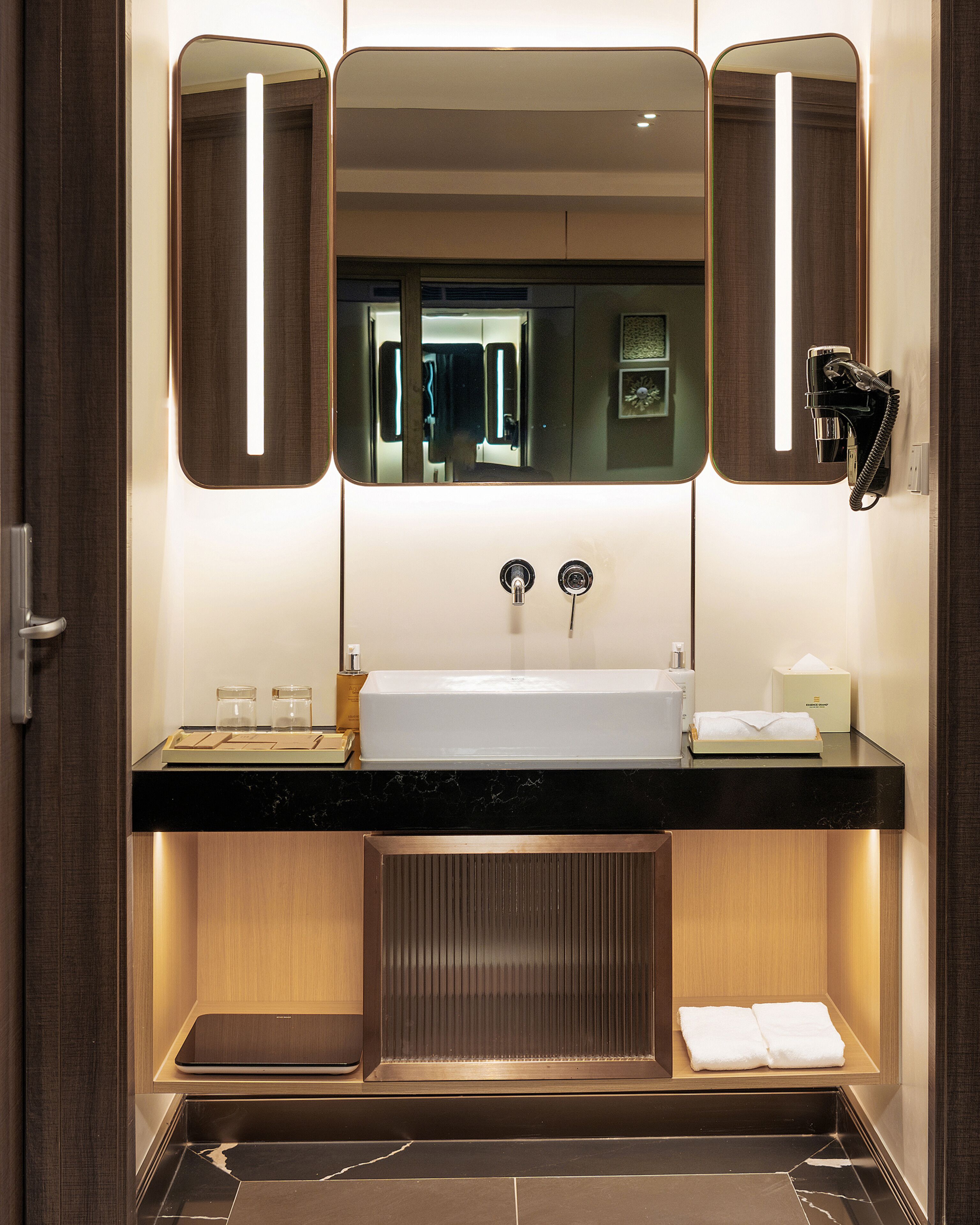 A modern bathroom with a large mirror, a sink, and a towel rack.