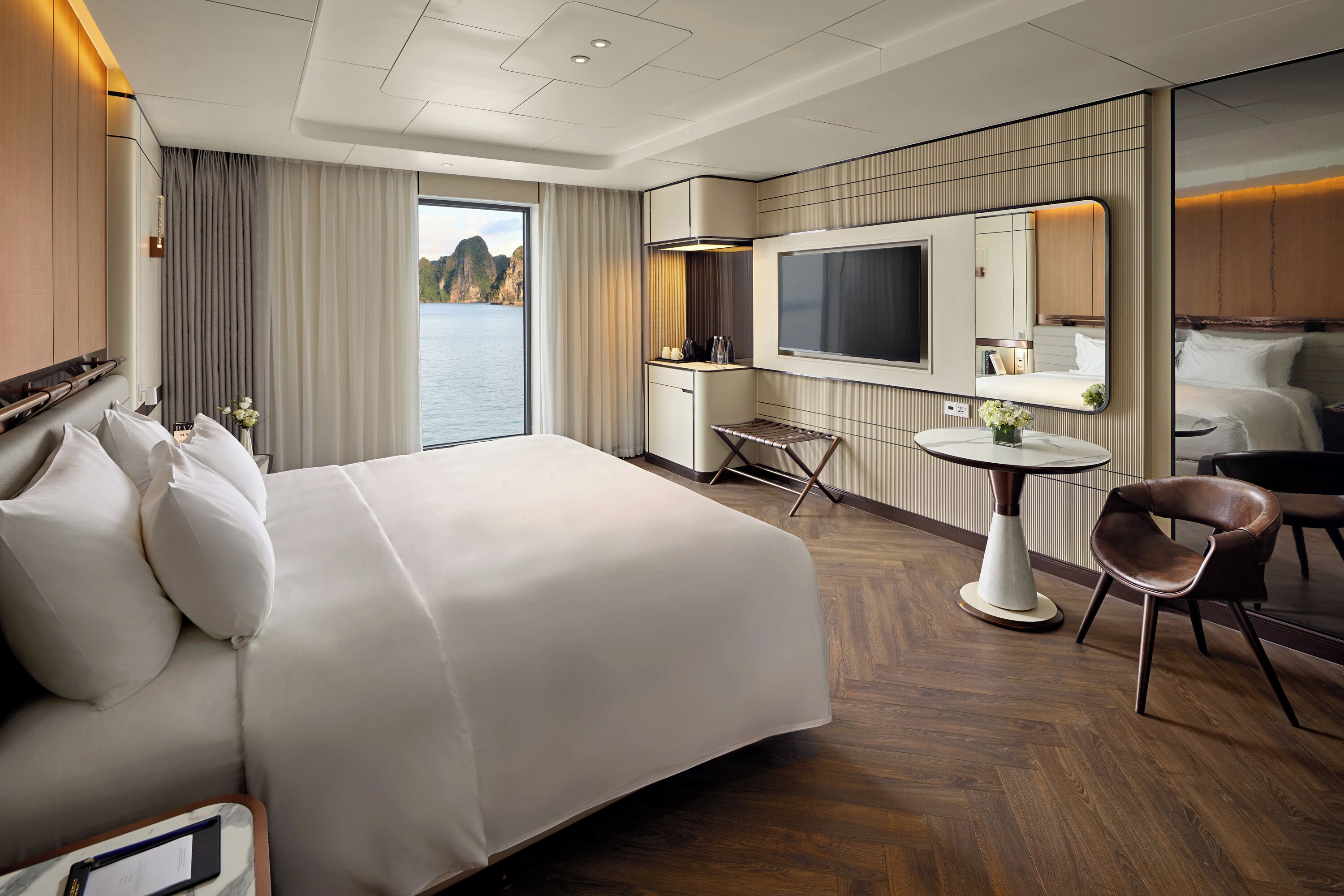 Habitación de hotel con una cama grande, televisión, escritorio, silla y vista al agua.