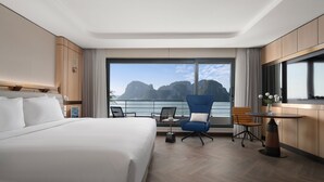 Habitación de hotel moderna con una cama grande, una mesa de comedor, dos sillas y vistas a un paisaje montañoso.