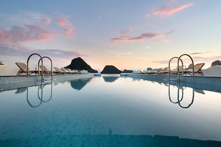Una piscina al aire libre, sombrillas, sillones reclinables de piscina