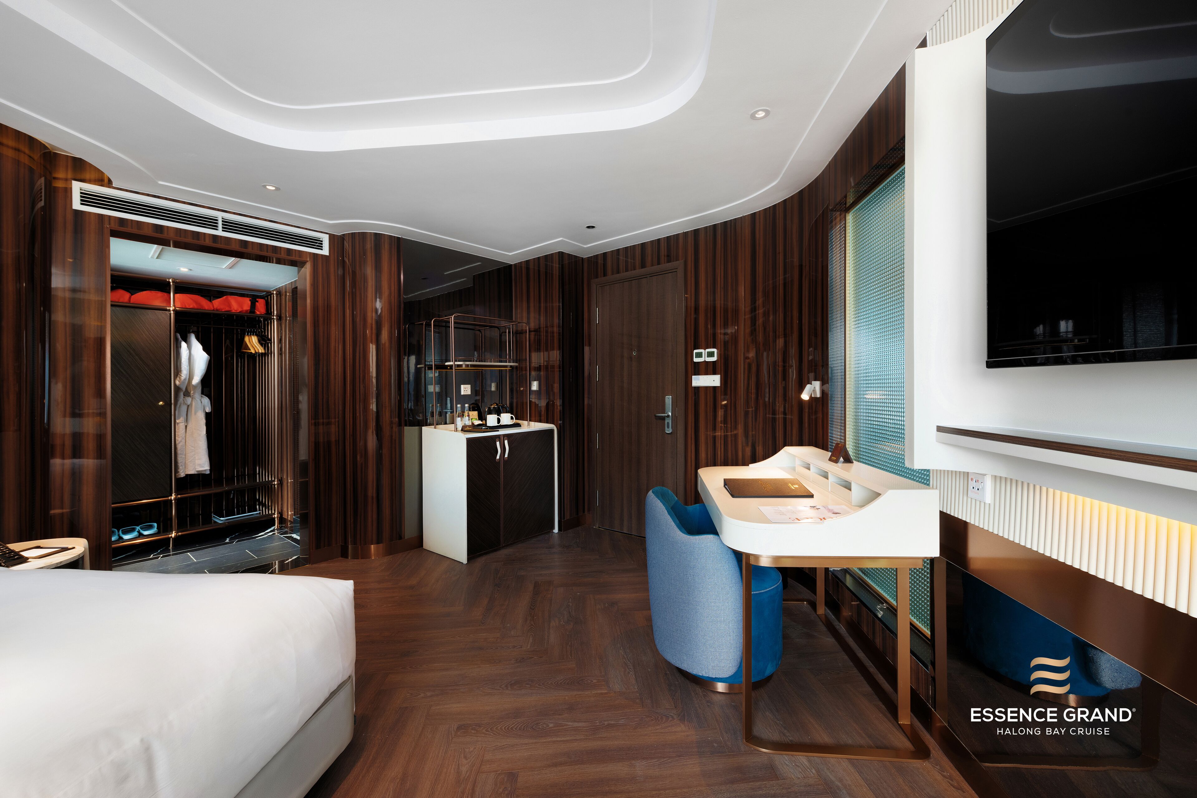 A modern hotel room with a bed, a vanity with a mirror, a seating area, and a wardrobe with a built-in closet.